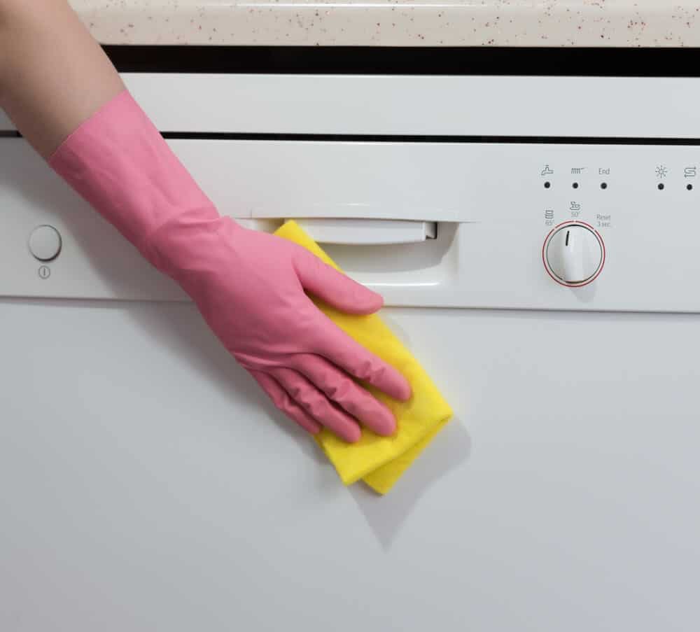 Person wiping down the outside of a dishwasher