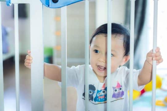 Baby behind a baby gate in a house
