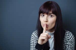 Woman putting her finger her over mouth to shush