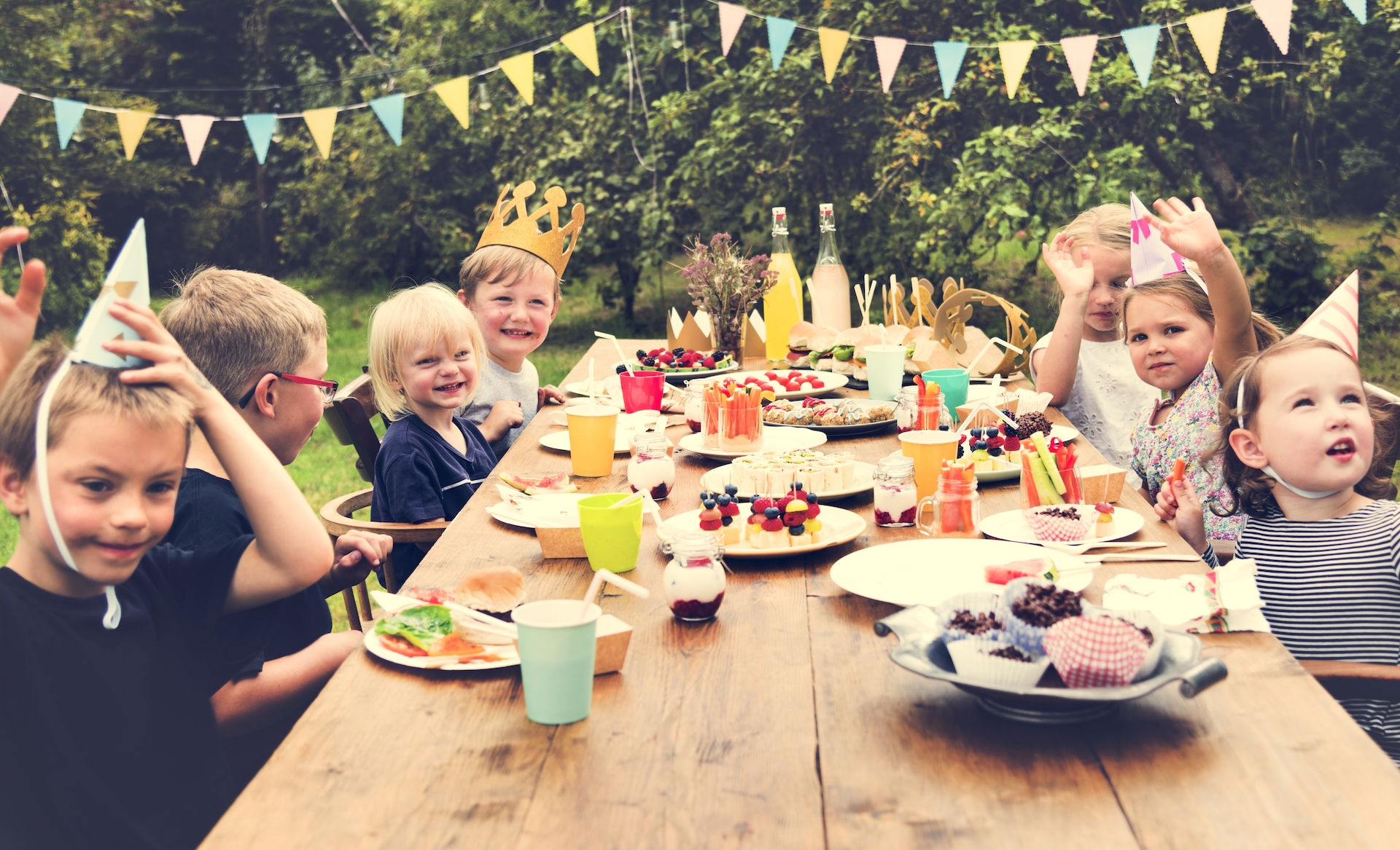 Kids around a wood table outside at a birthday party
