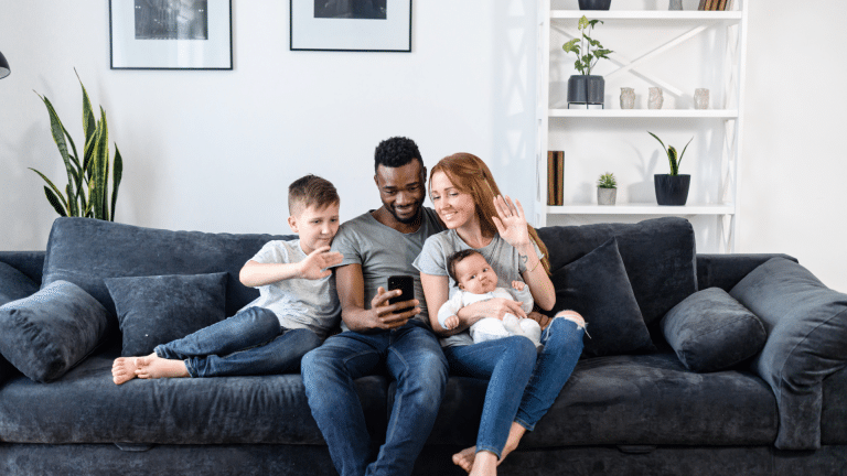 Family sitting on an extra deep couch, facetiming with someone