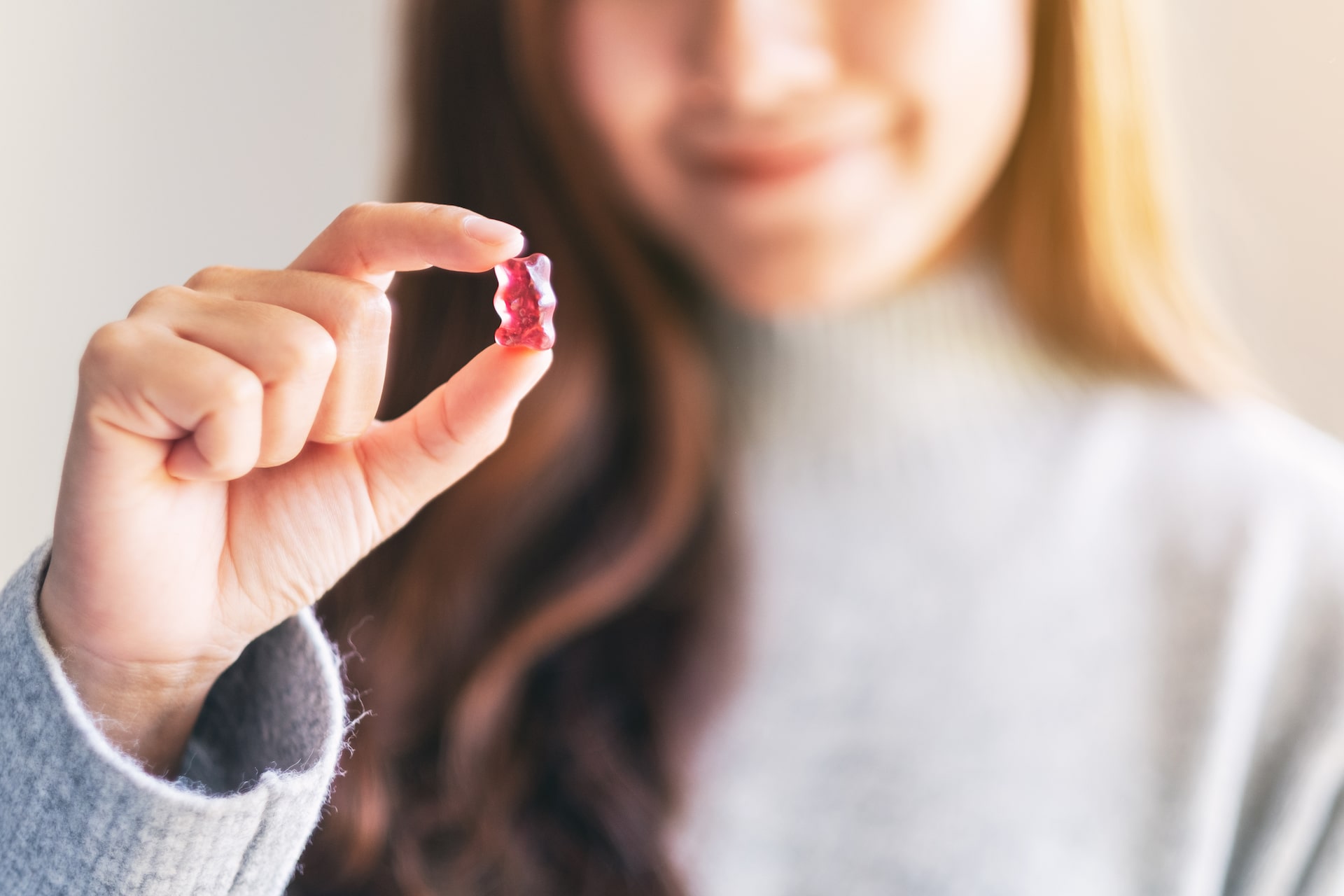 Woman holding a gummy bear up to the camera