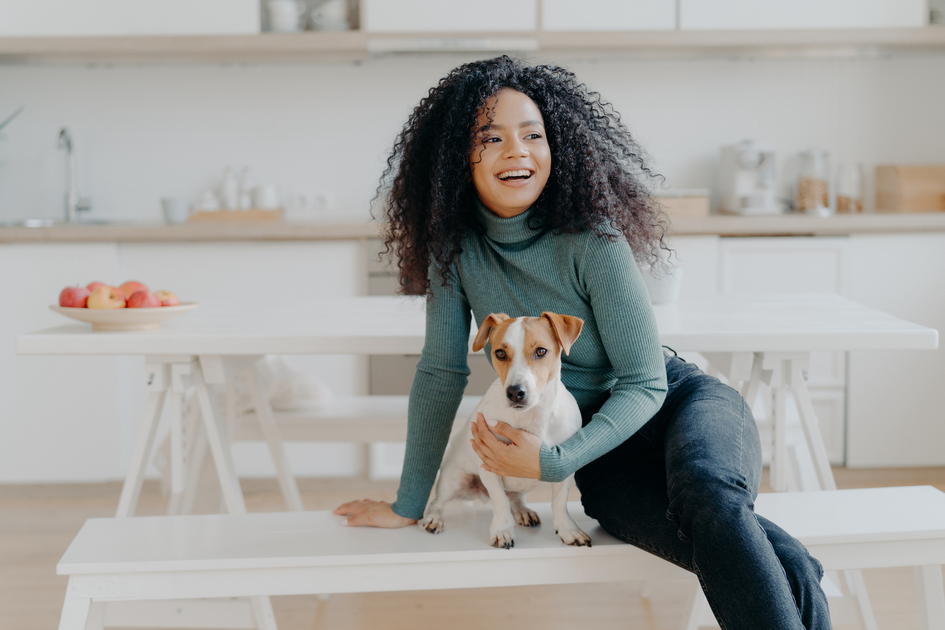 Woman sitting on a bench in her kitchen with her Jack Russel Terrier
