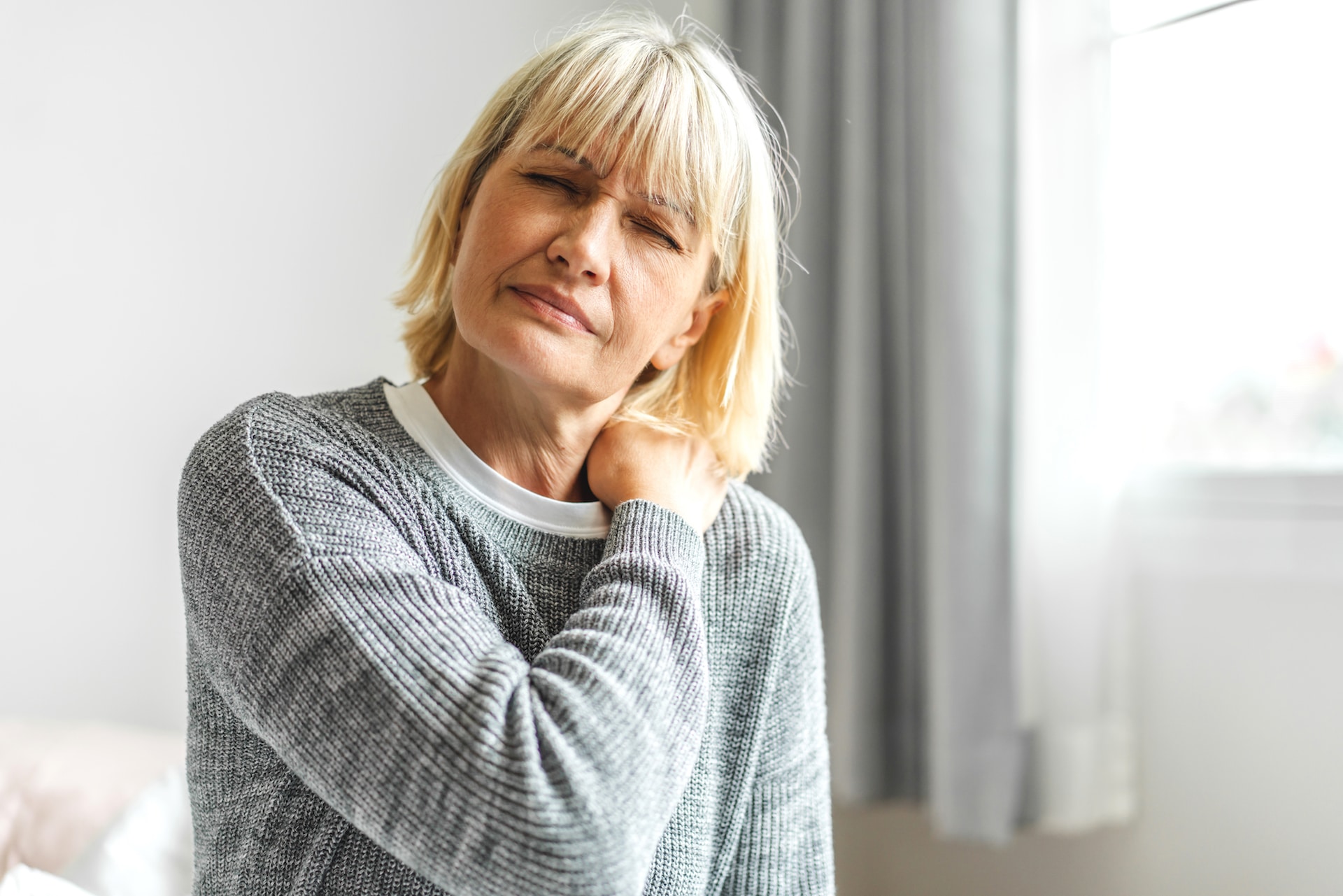 Woman holding her shoulder in her living room