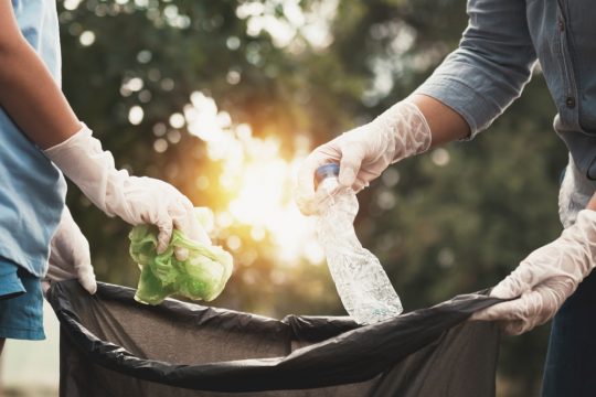 Close up of people throwing trash away that was left outside