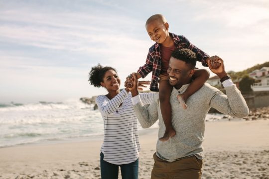 Family having fun on a beach, son on his father's shoulders