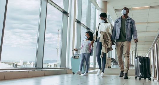 Family walking through airport in masks
