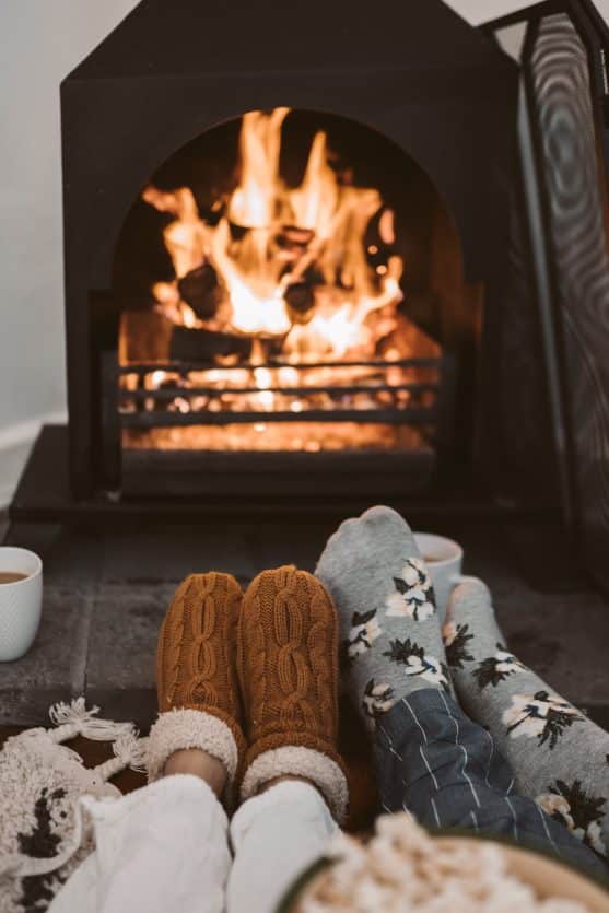 couple snuggled next to fireplace wearing socks